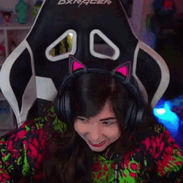 a woman wearing headphones with cat ears on her head is sitting in a chair .