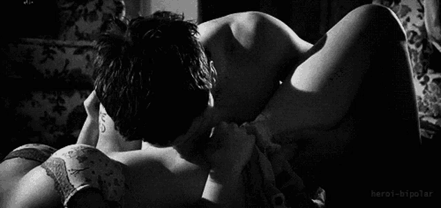 a black and white photo of a man kissing a woman on the neck .