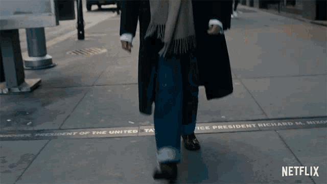 a person walking down a sidewalk with a netflix logo on the bottom right