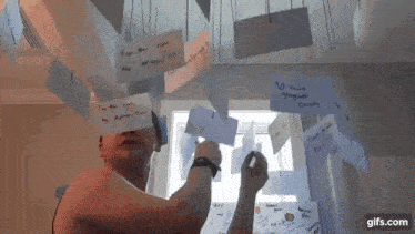 a man is writing on a piece of paper hanging from a ceiling .