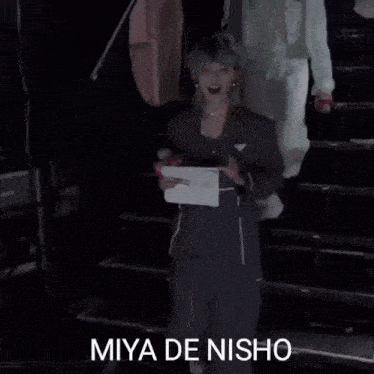 a person with green hair is holding a piece of paper and a microphone in a dark room .