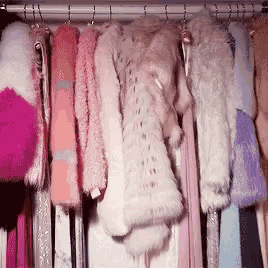 a closet filled with lots of pink and white fur coats and dresses