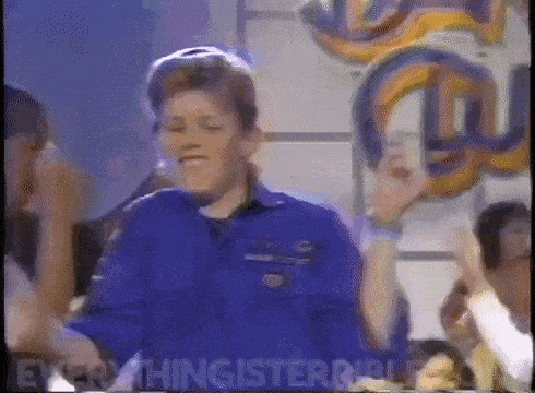 a man in a blue shirt is dancing in front of a crowd .