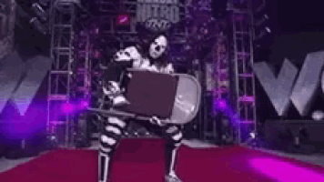 a person is standing on a red carpet in front of a stage holding a chair .