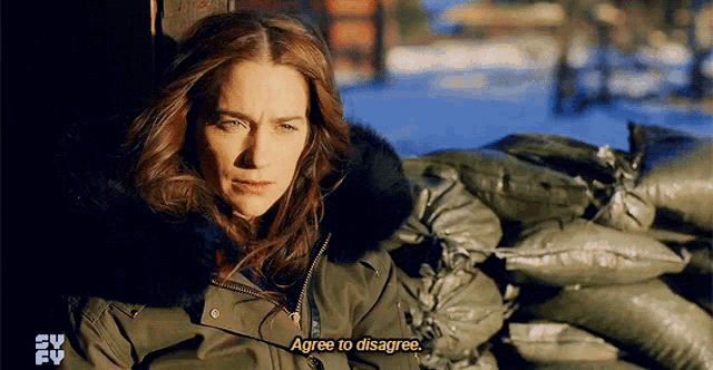 a woman in a parka says " agree to disagree " in front of a pile of bags