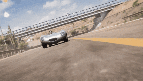 a silver car is driving under a bridge on a road