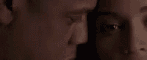 a close up of a man and woman 's faces looking at each other .