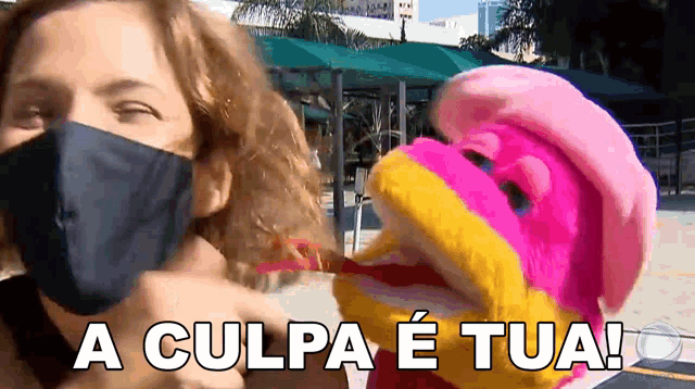 a woman wearing a mask is talking to a stuffed animal with the words a culpa e tua