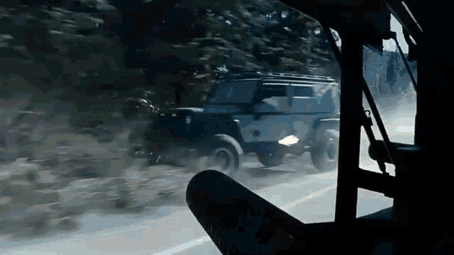 a jeep is driving down a road with a lot of dust coming out of it