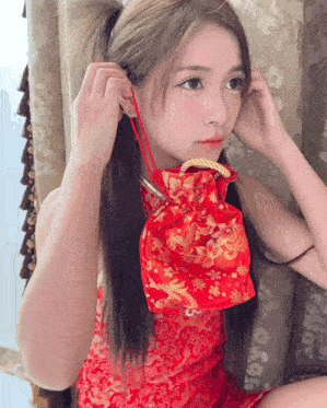 a woman in a red dress is holding a small red bag