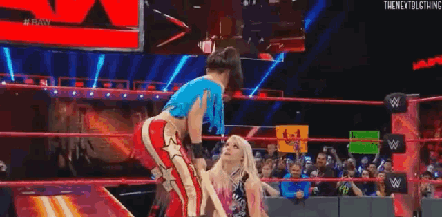 a wrestler is carrying a child on her shoulders in a wrestling ring .