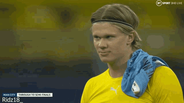 a man in a yellow shirt with a blue towel around his neck