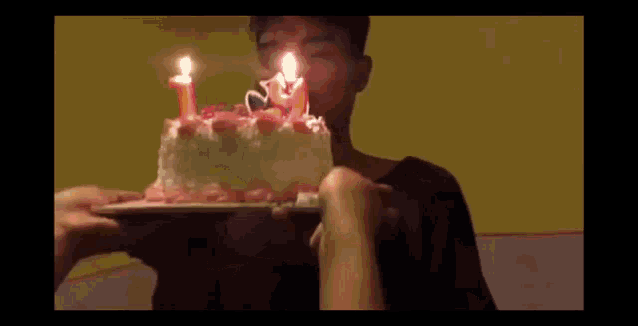 a boy blows out candles on a birthday cake
