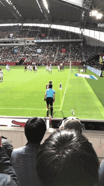 a referee stands on the corner of a soccer field watching a soccer game