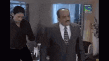 a man in a suit and tie is standing next to a woman in a black shirt in a room .