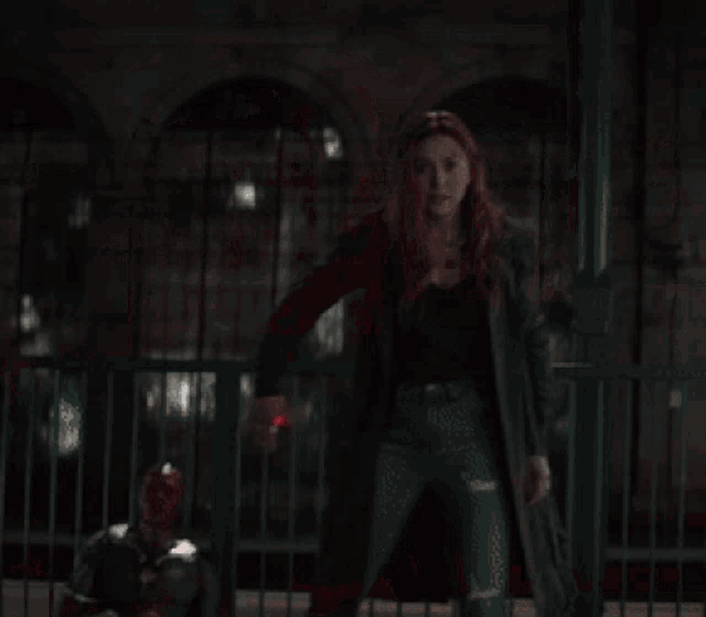 a woman is standing on a bridge with red lights coming out of her hands