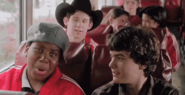 a group of young boys are sitting on a bus wearing cowboy hats and jackets .