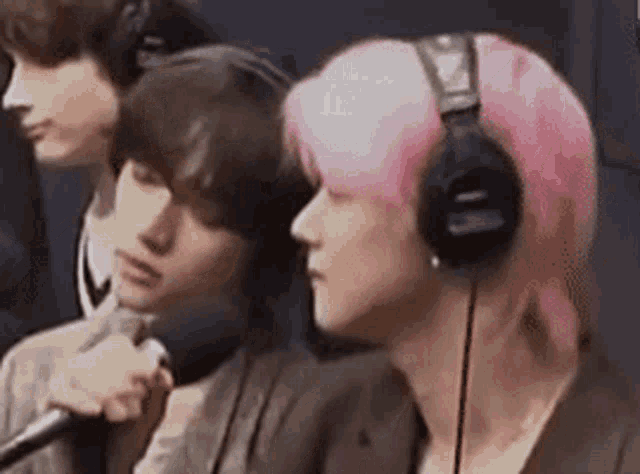 a woman with pink hair is wearing headphones and a microphone .