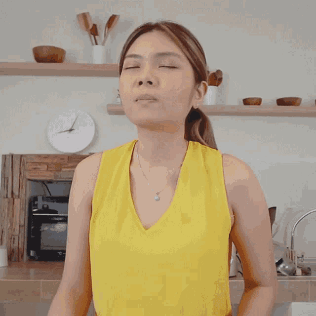 a woman in a yellow tank top is giving a thumbs up sign