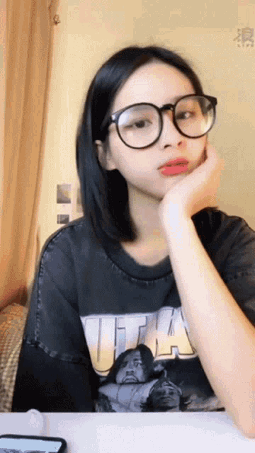 a woman wearing glasses and a t-shirt that says t-ha on it