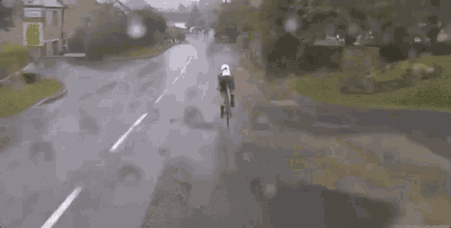 a person is riding a bike down a wet road .