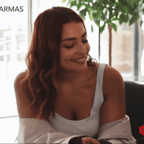 a woman with red hair is smiling in front of a banner that says armas