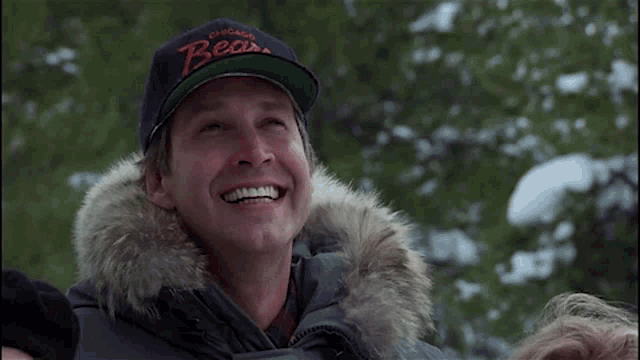 a man wearing a chicago bears hat is smiling in the snow