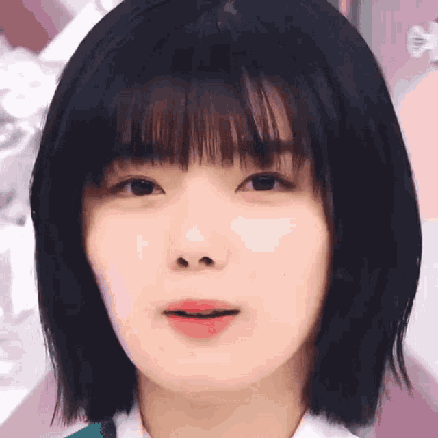 a close up of a girl 's face with short black hair and bangs .