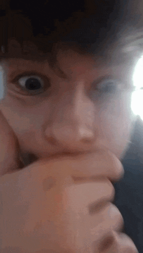 a close up of a person 's face with their hand on their mouth .