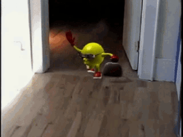 a yellow pac man walking down a hallway with a broom