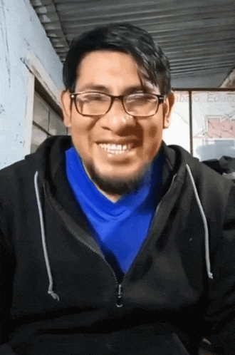 a man with glasses and a blue shirt smiles for the camera