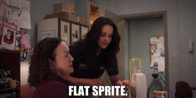 two women are sitting at a table and one of them is talking to the other and they are talking about flat sprite .