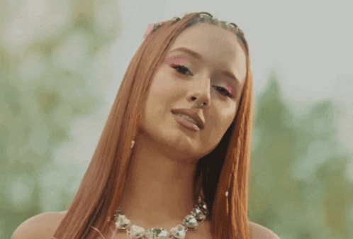 a woman with long red hair is wearing a necklace with rhinestones