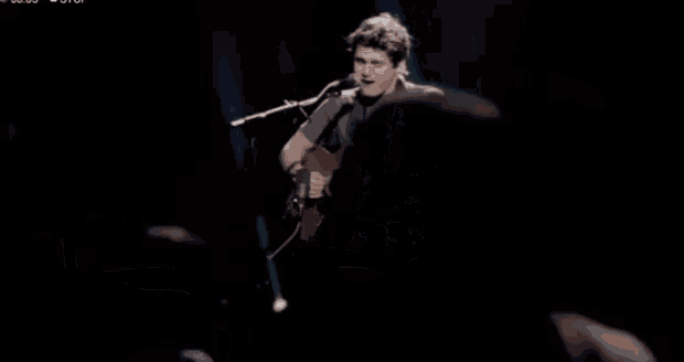 a man is playing a guitar and singing into a microphone on a stage