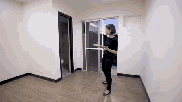 a woman standing in an empty room holding a sliding glass door