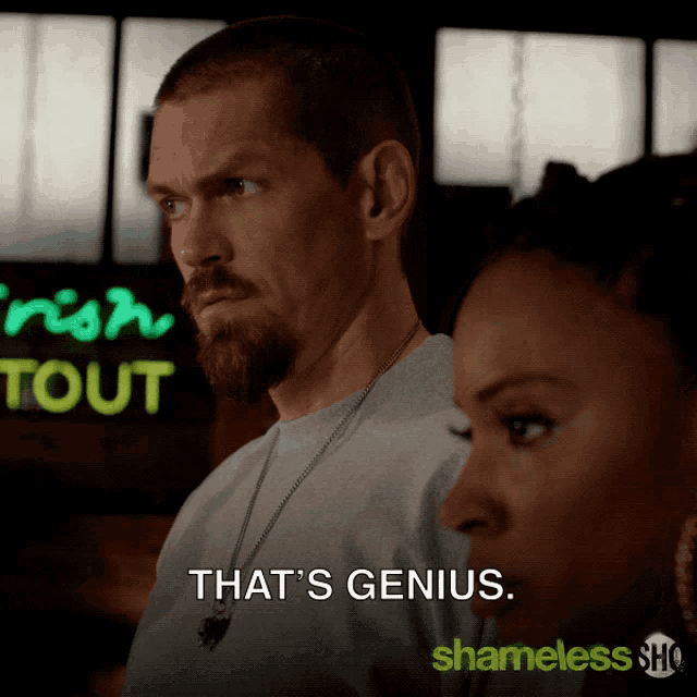 a man and a woman are standing in front of a neon sign that says " that 's genius "