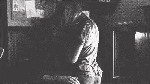 a black and white photo of a man and a woman hugging each other .