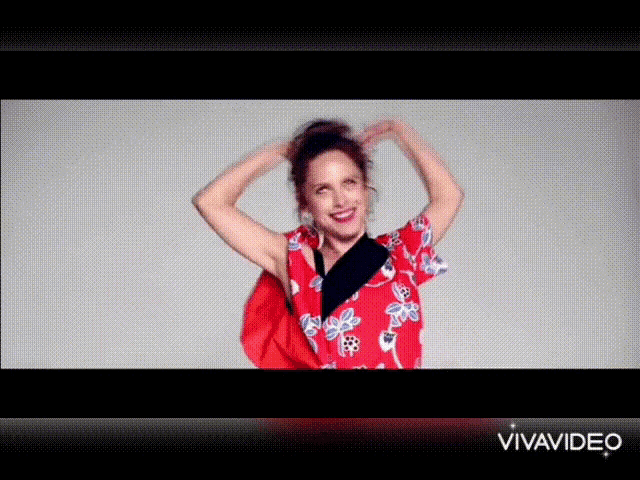 a woman in a red floral shirt is smiling and holding her hair