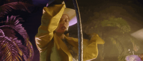 a woman in a yellow jacket and cowboy hat is holding a hula hoop ..