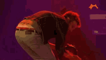 a man is playing a guitar on a stage with a red light behind him