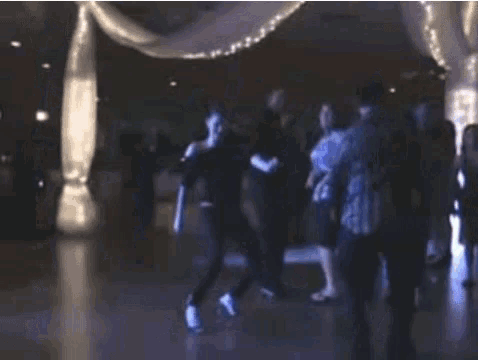 a group of people are dancing in a dark room