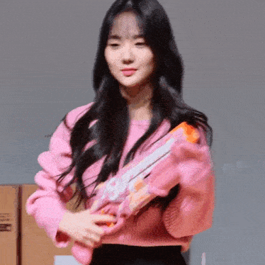a woman in a pink sweater is holding a water gun .