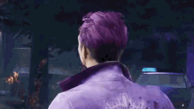 a man with purple hair is standing in front of a red car .