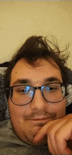 a man wearing glasses and a beard is laying on a bed