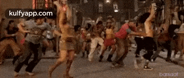 a group of people are dancing on a street in a crowd .
