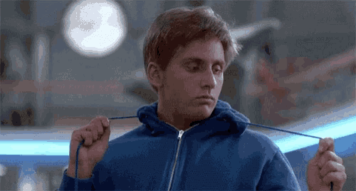 a young man in a blue hoodie is tying his hoodie .