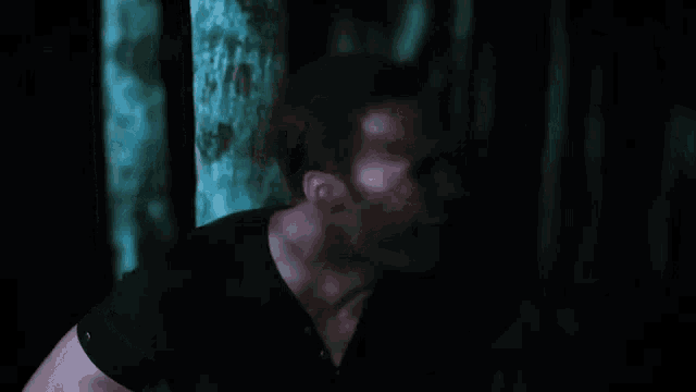 a man in a black shirt is laughing with his mouth open