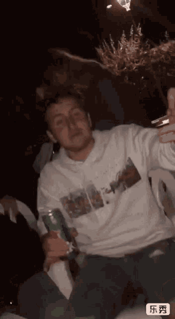 a man in a white sweatshirt is holding a can of soda and a cigarette ..