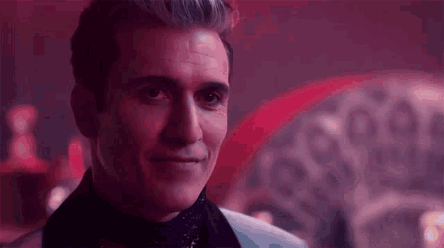 a close up of a man 's face in a dark room with a red background .