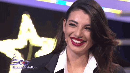 a woman with red lipstick is smiling in front of a sign that says " egrandefratello "
